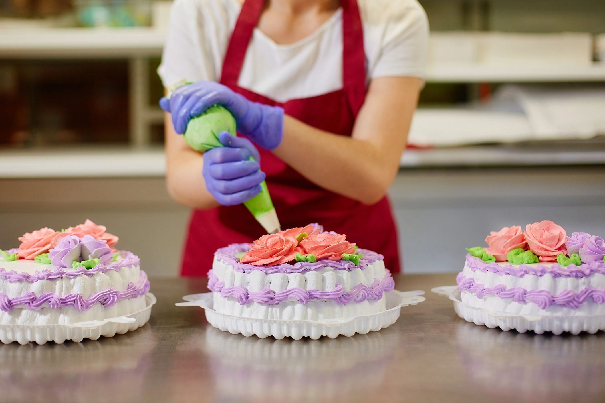 Pastry chef piping cream flowers to decorate a cake