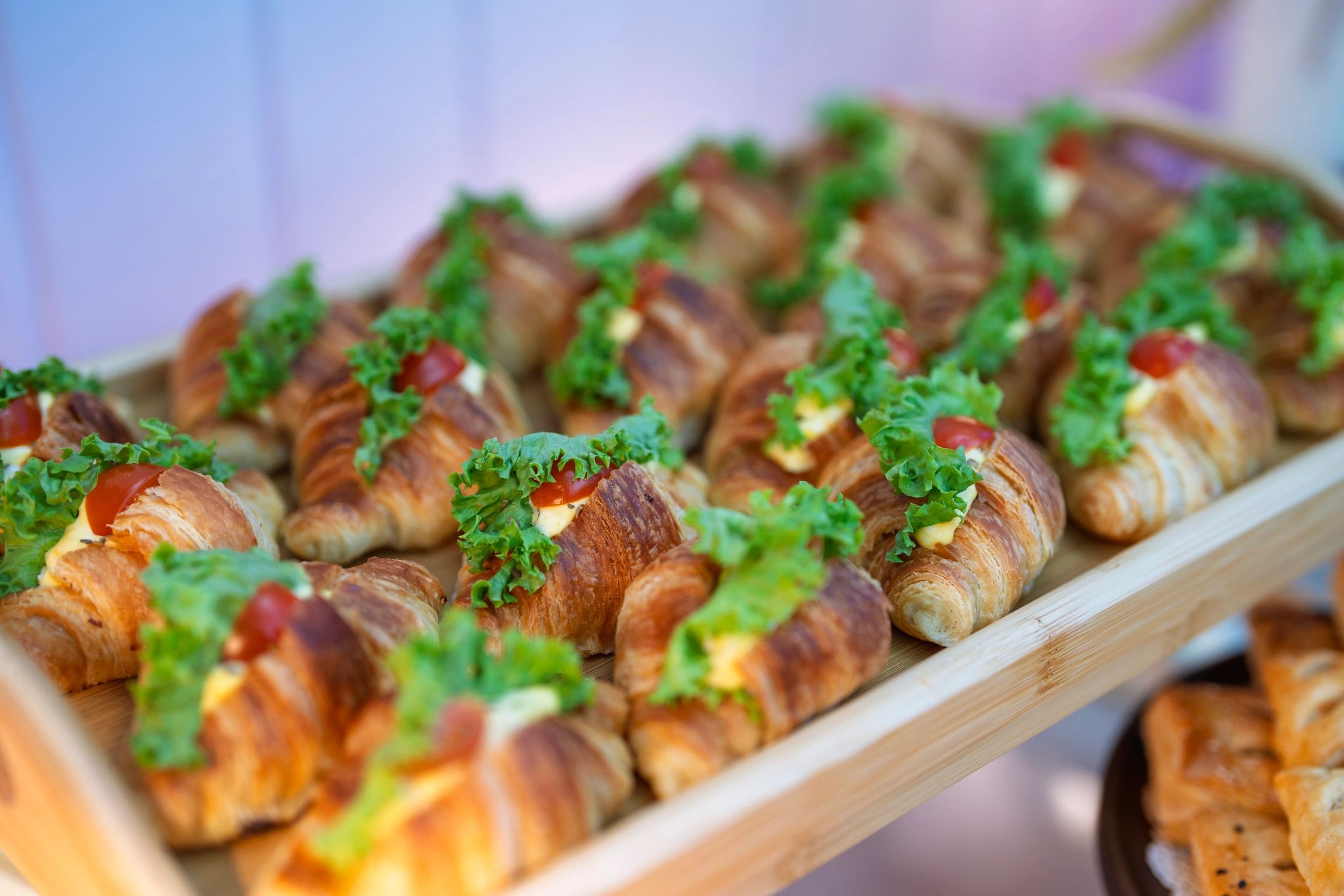 Mini croissant sandwiches arranged on a wooden tray